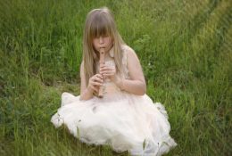 Child playing the recorder in a field